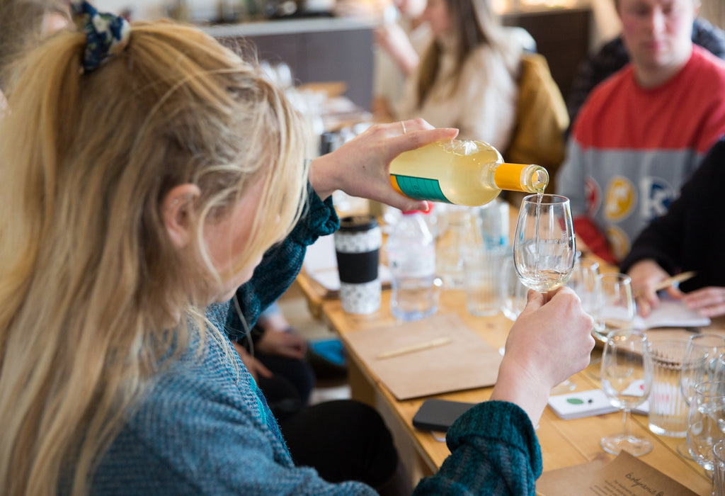 Student pouring a Greek Natural wine into a tasting glass